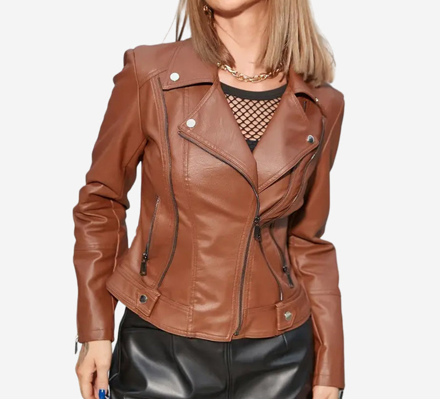 A woman wearing a brown leather biker jacket with asymmetrical zip closure, zippered cuffs, and multiple pockets over a black top and paired with a leather-look skirt.